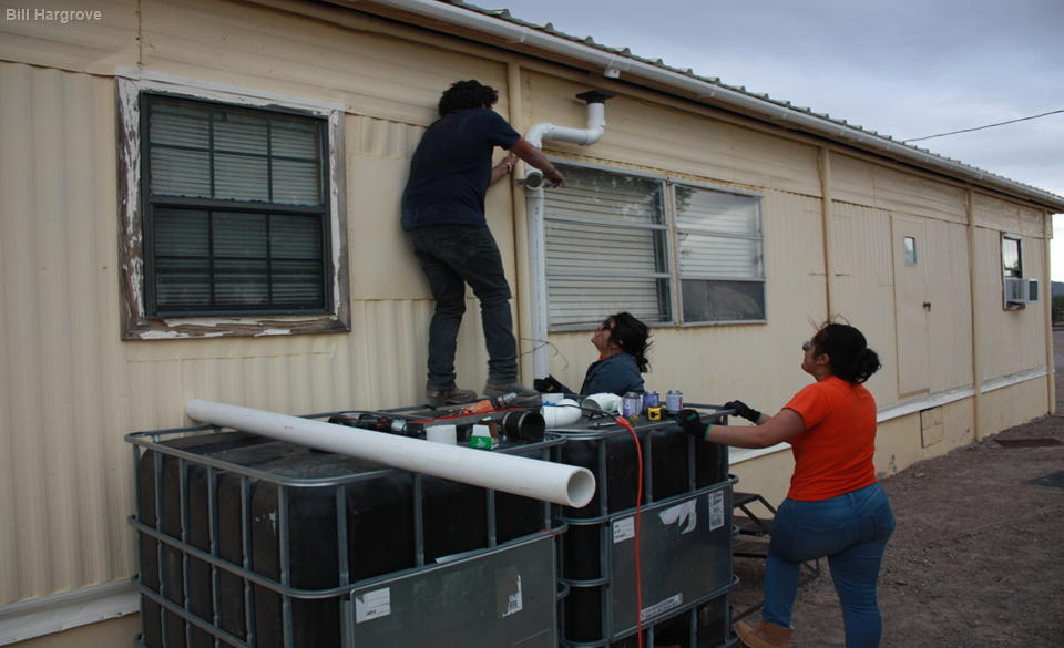 Students install a rainwater harvesting setup on a house near Presidio, Texas.